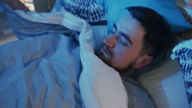Guy waking up for drinking water at night. Thirst after party. Young man sitting on bed, holding glass in hand. Taste. Help from friend. Indoors.