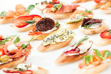 selective focus of italian bruschetta with dried tomatoes, avocado, prosciutto and herbs