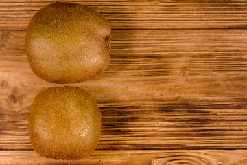 Two kiwi fruits on a wooden table. Top view