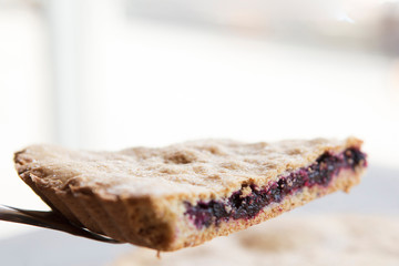 A stylish photo of a piece of a thin pie with fruit filling. Brown cake with berries.