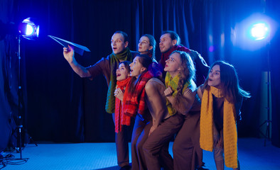 The actors on the stage play a performance and look at a blue paper plane.