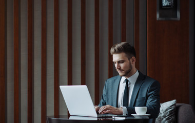 Fototapeta premium Young businessman working on a plan of Internet project on the laptop. Man discusses business matters by phone. Working computer for internet research. Digital marketing. Development