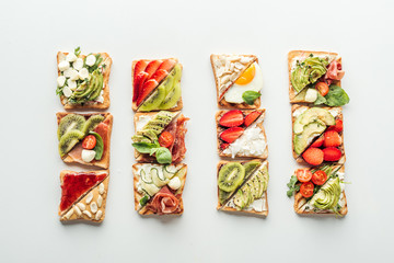 top view of tasty toasts with fruits, vegetables and basil isolated on white