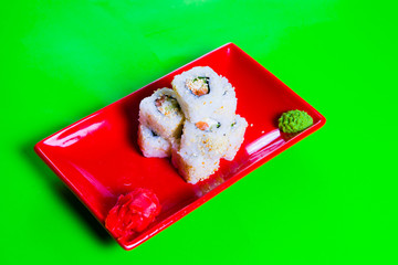 A portion of sushi on a red plate. green background
