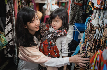 Obraz premium asian mom and kid shopping batik dress in traditional market