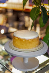 Stylish white cake standing on a cake stand on a high stalk