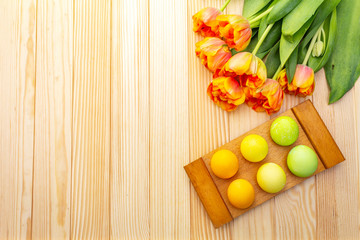 Easter spring concept. Gentle tulip and eggs on wooden stand and background. Card, wallpaper, copy space, top view.
