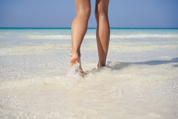 Woman legs walking on the beach sand.