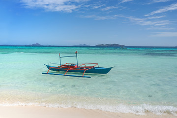 A small blue boat on a tropical beach