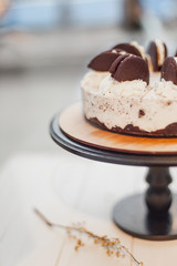 Stylish white cake standing on a cake stand on a high stalk