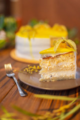 delicious and appetizing piece of high cake with yellow fruits on a plate on the background of a cake