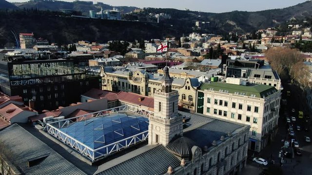 Gorgeous aerial footage of Tbilisi with the flag of Georgia on one of the buildings, 4k