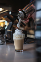 the process of preparing a delicious coffee drink with whipped cream that is decorated with coffee with milk
