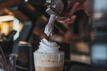 the process of preparing a delicious coffee drink with whipped cream that is decorated with coffee...