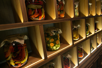 Different canned vegetable preserves in jars on the wooden shelf. Granny's food.