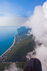 high flight against the wall of clouds over the blue sea view of a paraglider pilot, summer vacation in the Caucasus in Abkhazia.