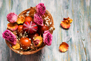 Obraz na płótnie Canvas basket with easter eggs and flowers on a wooden table