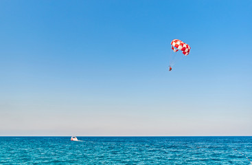 Fototapeta na wymiar Parasailing flying against the background of the blue sky. The concept of summer holidays, vacation.