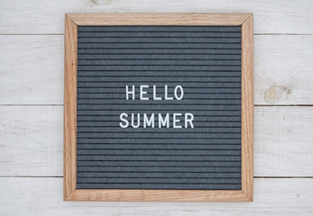 English text Hello summer on a letter Board in white letters on a gray background