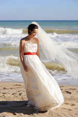 Fototapeta na wymiar Pretty young bride walking on a sea beach