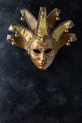 Venetian mask on a black background. Gilded mask on a stone black wall background.