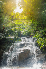 Running water of tropical waterfall in rainforest under sun light
