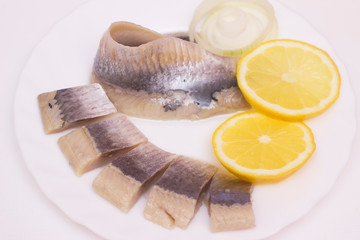 marinated herring fillet with onion and lemon on white plate, top view with copy space