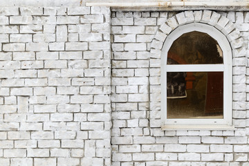 The brick wall painted with white paint with a window