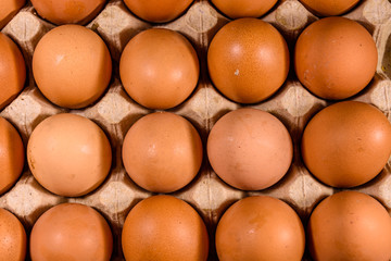 Pile of the hen eggs in paper tray on wooden table. Top view