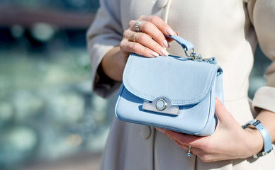 Blue little handbag in female hands. Close-up leather handbag. Women walking in the city. Girl in a...