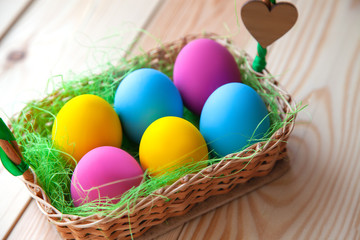 Fototapeta na wymiar colored easter eggs in wicker basket, on wooden background