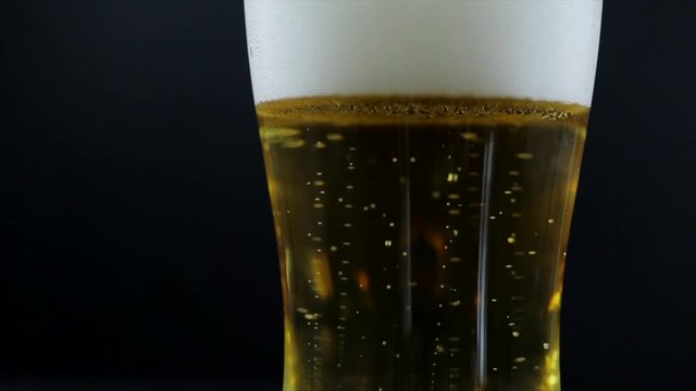 Glass of beer with foam on a dark background
