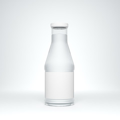 Transparent glass bottle with metal cap and label filled by still water on the white background.
