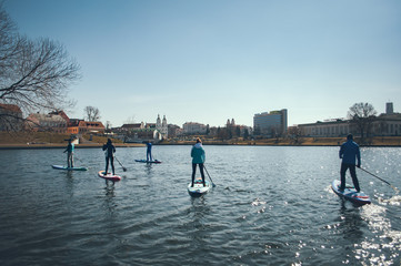 A group of people floating on the paddle boards in the background of the city, outdoor activities on the water, the city of Minsk in the background,