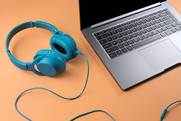Obraz na płótnie Canvas Photo of stylish modern computer or notebook and blue cyan headphones over beige background.