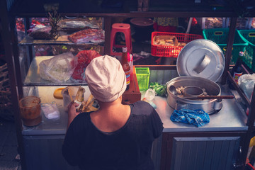 Asian food, street food. Woman prepares food on a mobile cart