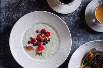 Menu at the cafe, Breakfast, Porridge with berries, Bulgur with coconut milk. Flatlay, Top view, Moody on black background, Darkstyle