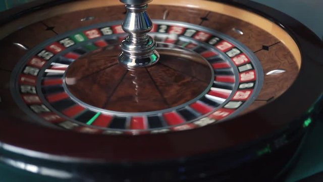 Pan shot left to right of casino roulette wheel spinning with a white ball inside. Casino roulette in motion, the spinning wheel ball. Roulette wheel running.