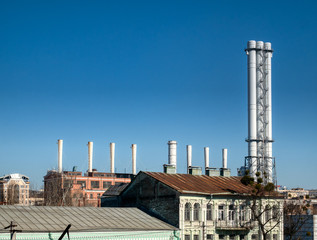 Tall factory pipes chimneys of light industry plant at industrial zone. outdoor image with clear blue sky