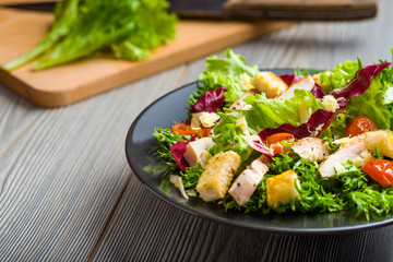 Healthy chicken salad with lettuce, grilled tomato, croutons, shredded cheese and grilled chicken