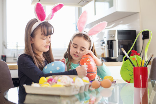 Little girls with Easter bunny ears holding colorful eggs