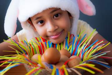 Happy easter! Close up cute girl wearing rabbit hat with chicken eggs in a basket. - 259133892