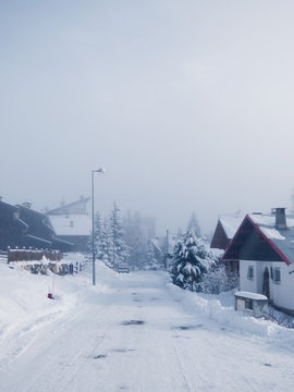 Route enneig&eacute;e d'un village sous la brume dans les Alpes fran&ccedil;aises