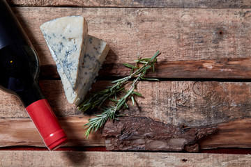 Red wine and ingredients for romantic dinner on the wooden background. Cheese and bread.