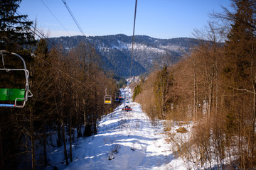 Winter mountains panorama with ski slopes and ski lifts on a cloudy day
