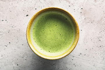 Top view of green tea matcha in a bowl on concrete surface. Single object