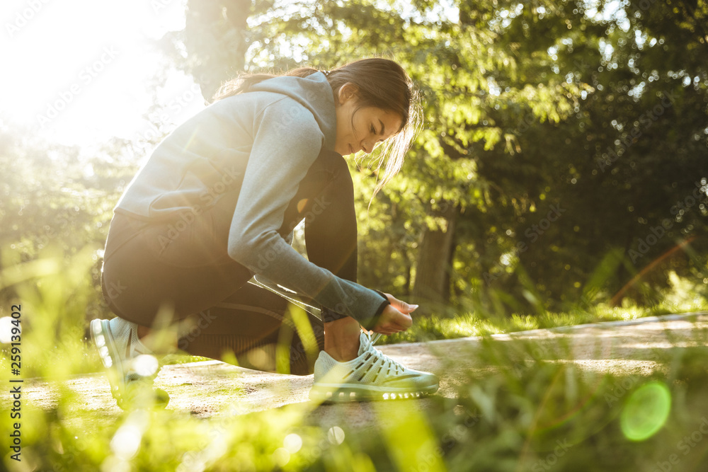 Sticker Attractive young fitness woman tying her shoelace