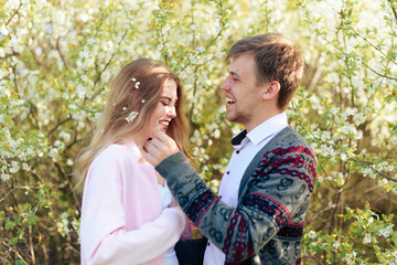 a young couple in love cuddles against the background of blooming spring cherry orchards 1