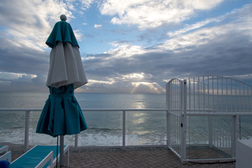 Parasol and footbridge to the beach in Miami with a sunrise