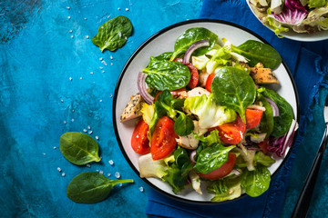 Green salad with chicken and vegetables top view.